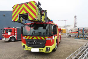 Feuerwehrfahrzeug mit Drehleiter im Einsatz auf einem Industrieareal, fotorealistische Darstellung von Feuerwehrtechnik und Rettungseinsatz.